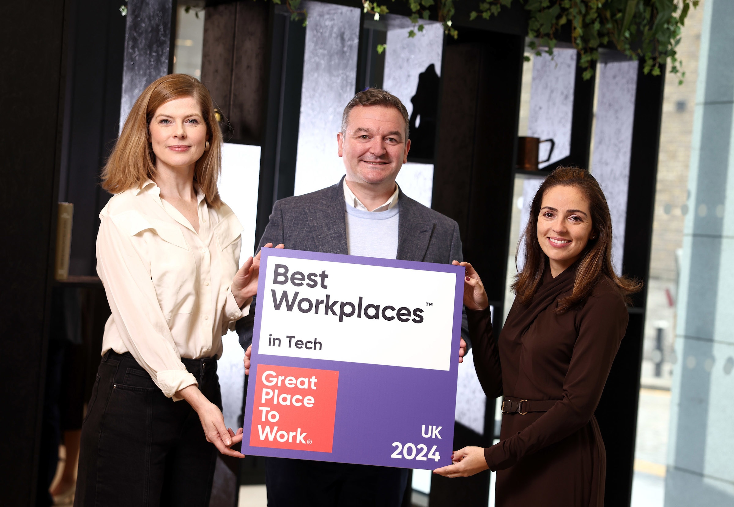 Photo of three employees holding a Best Workplaces in Tech logo