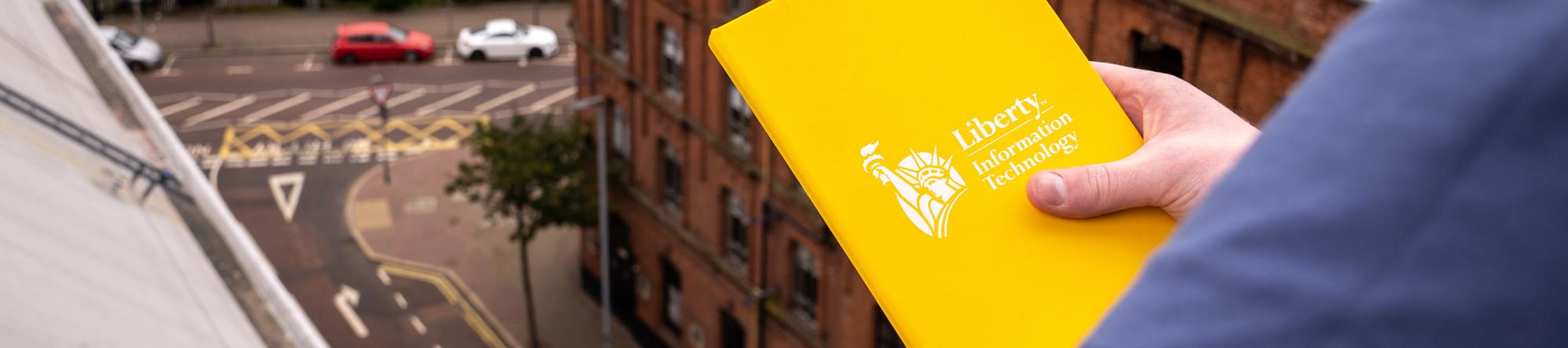 Photo of hand holding notebook, looking over street from high up